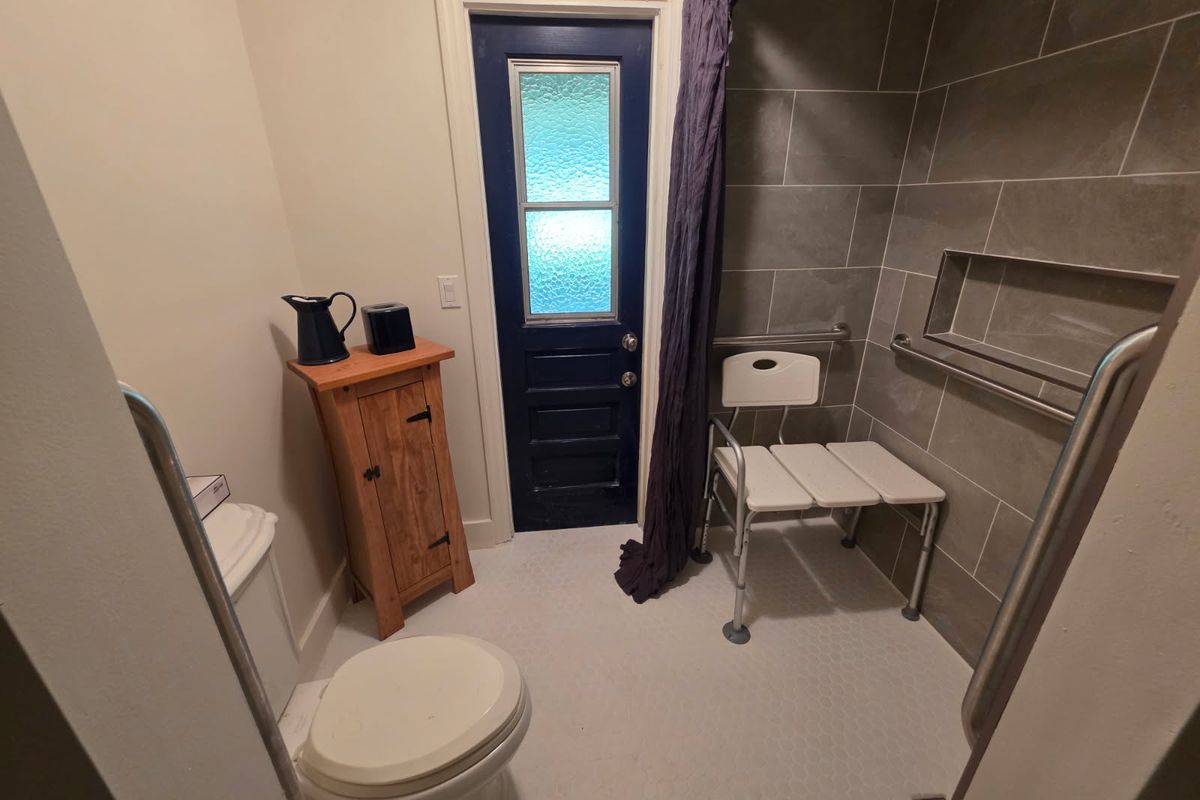 The bathroom after the work: the bath replaced with a tiled walk-in shower with a bench and grab bars