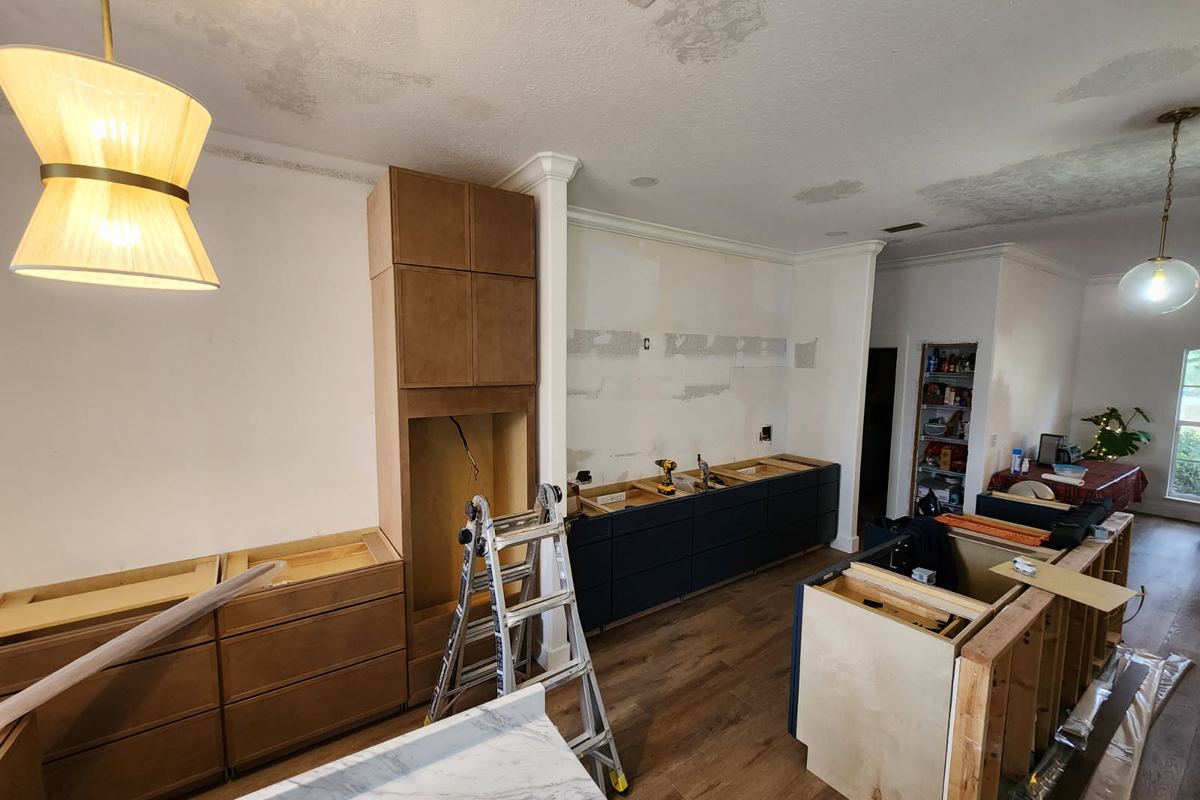 The same kitchen mid-remodel, with cabinet boxes going in and a ladder in the room